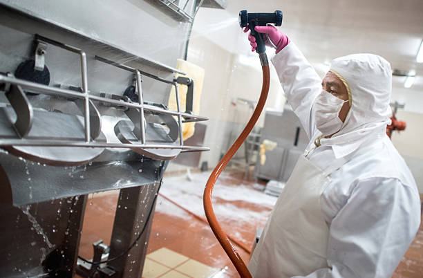 Man washing machines at a factory Man washing machines at a factory with a hose food processing plant stock pictures, royalty-free photos & images