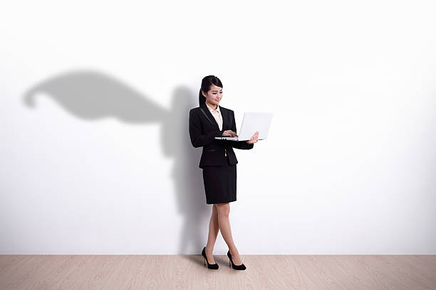 Superhero Business Woman with computer Superhero Business Woman using laptop computer with white wall background, great for your design or text, asian heroes photos stock pictures, royalty-free photos & images