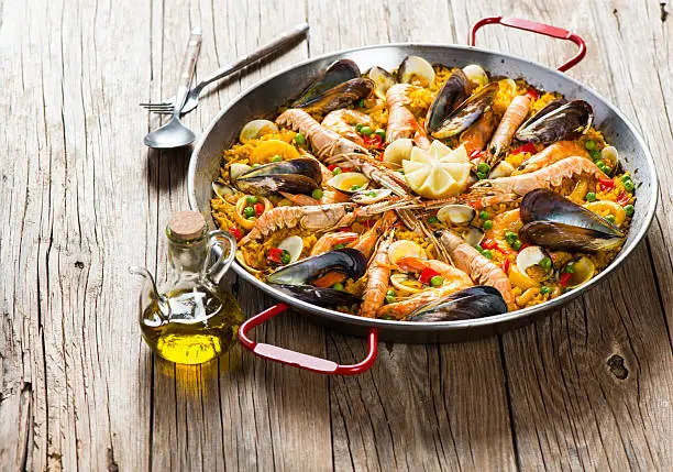 Spanish dish paella with seafood  in traditional pan on a rustic wooden table