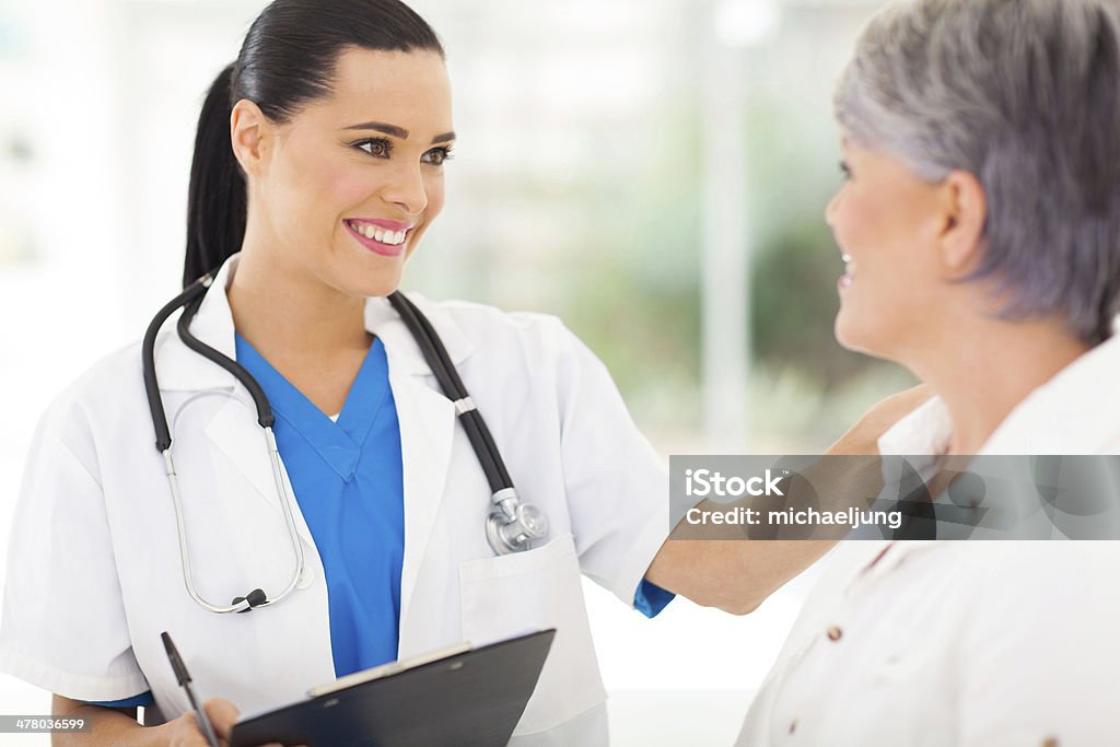 female doctor comforting middle aged patient friendly female doctor comforting middle aged patient in hospital Adult Stock Photo