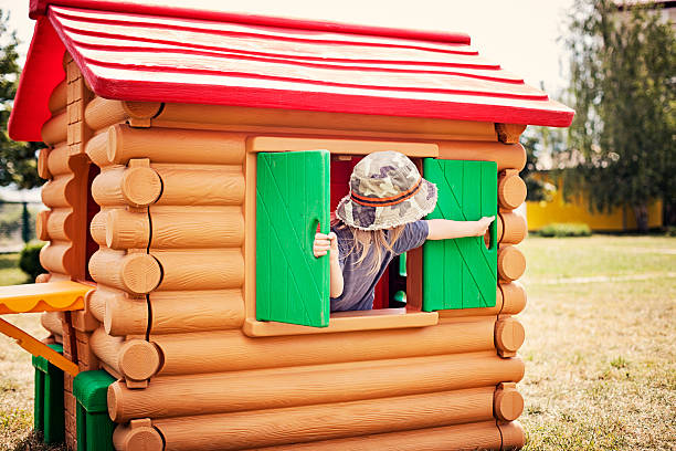 Little boy playing in the playhouse Little boy (3-4) closing (or opening) the playhouse window. kids play house stock pictures, royalty-free photos & images