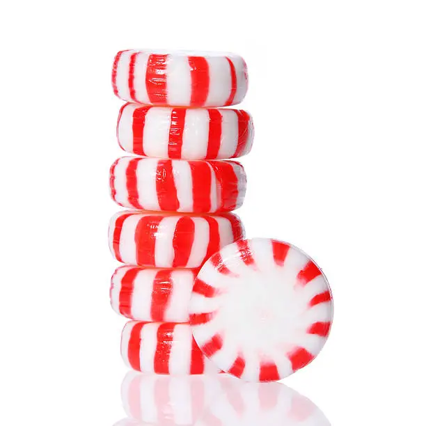 Peppermint candy tower isolated on white. Red striped peppermint Christmas candy, macro.