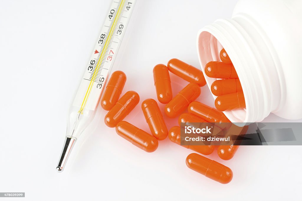 Pílulas laranja e termômetros em fundo branco - Foto de stock de Antibiotico royalty-free