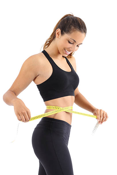 Sportswoman measuring her waist with a measure tape Sportswoman measuring her waist with a measure tape isolated on a white background exercising tape measure women healthy lifestyle stock pictures, royalty-free photos & images