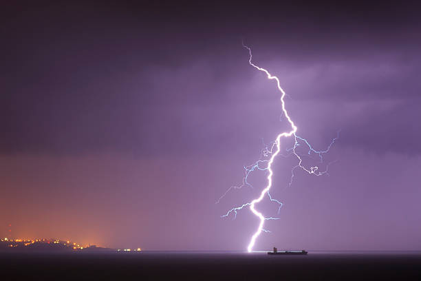 Lightning strikes in the sea, close to the cargo ship.