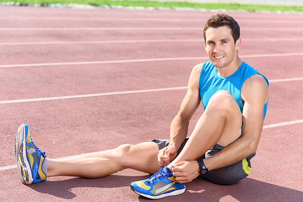 istock Man sitting on floor and lacing sneakers 478044106