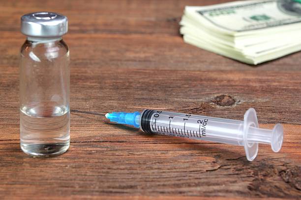 istock Money Wad, Syringe And Vial On Rough Wood Table 478046018