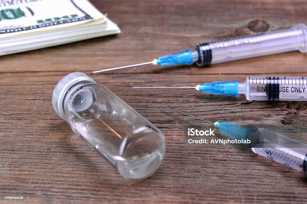 Money Wad, Syringe And Vial On Rough Wood Table Money Wad, Syringe And Vial On Rough Wood Table. Crime, Fraud, Bribe, High Insurance Or Treatment Fees Price, Sport Dope, Doctor  Mistake Or  Drug Addiction  Concept 2015 Stock Photo