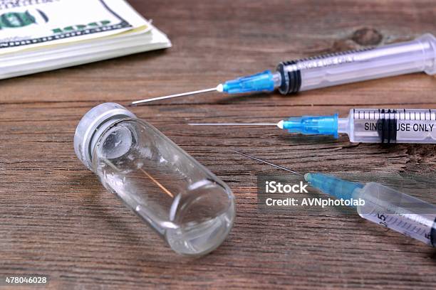 Money Wad Syringe And Vial On Rough Wood Table Stock Photo - Download Image Now - 2015, Birth Control Pill, Bribing