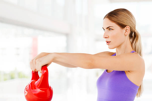 istock Woman Looking Away Lifting Kettle Bell In Gym 478046621