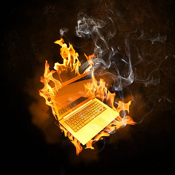 Laptop in fire flames stock photo