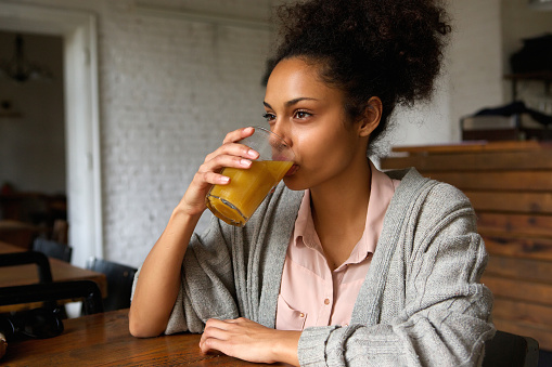 Close up portrait of a young mixed race woman drinking orange juice