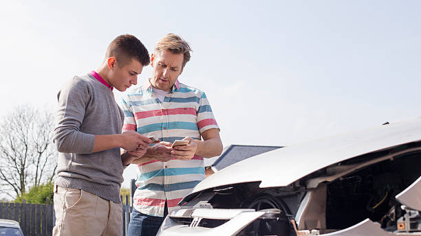Exchanging Insurance Details One young motorist swapping insurance details with another mature motorist after a traffic collision. misfortune photos stock pictures, royalty-free photos & images