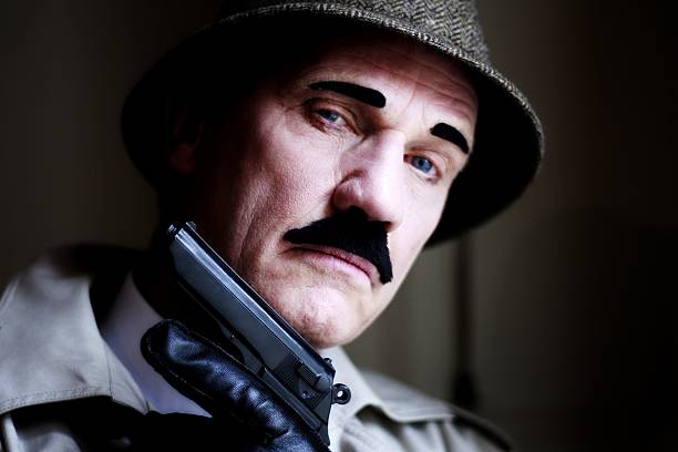maduro hombre disfrazado de detective con pistola - spy gun men humor fotografías e imágenes de stock