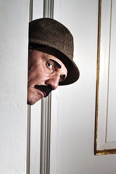 istock mature man dressed as detective peeping around door 478066928