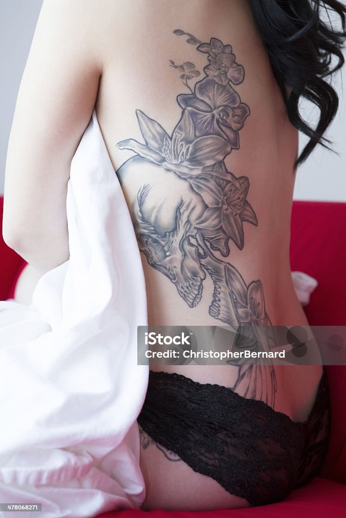 Mulher bonita com tatuagem nas costas, sentado no sofá vermelho - Foto de stock de 20-24 Anos royalty-free