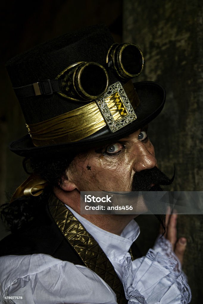 man dressed in steampunk, victorian clothing, dark wall background man dressed in Steampunk clothing , a sub culture style that combines victorian dress with science fiction, industry and fantasy, 2015 Stock Photo