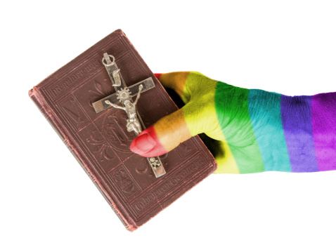 Hand (woman) holding a very old bible, rainbow flag