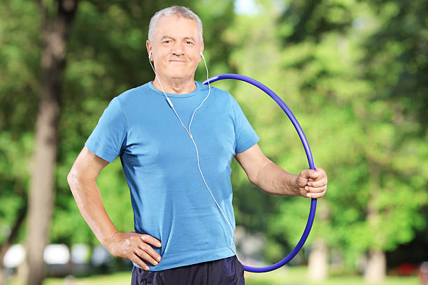 istock Smiling mature man with headphones holding a hula hoop 478096455