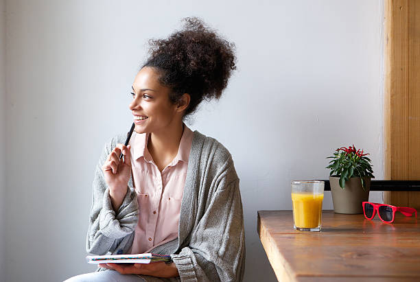 heureuse jeune femme assise à la maison avec un stylo et un papier - tracer photos et images de collection