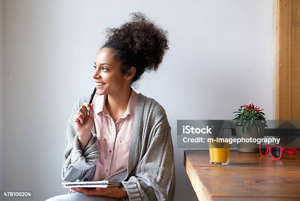 Happy Young Woman Sitting At Home With Pen And Paper Stock Photo - Download Image Now