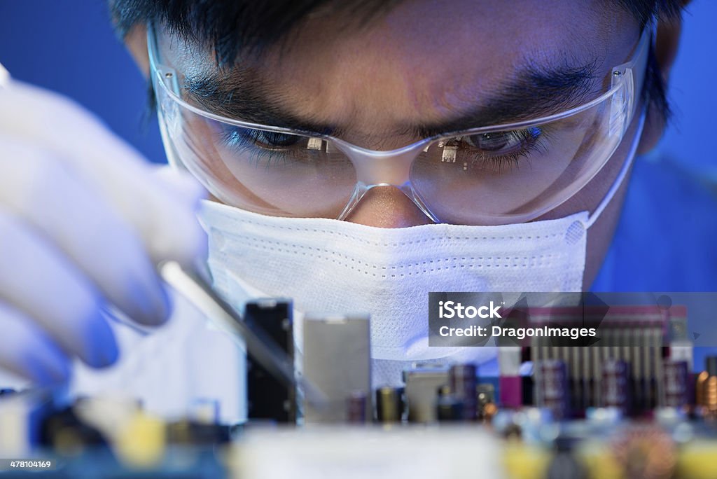 Electronic engineer at work Close-up image of an engineer concentrated on electronic assembling on the foreground Adult Stock Photo