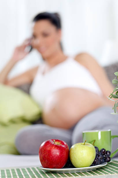 istock Pregnant woman with fruit on table 478108947