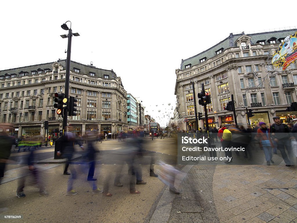 Oxford circus London, UK - November 1, 2013: Few blurred persons crossing the street while, some are waiting for light.  In background are surrounding houses and some Christmas decoration on Oxford street with grey sky above. Activity Stock Photo