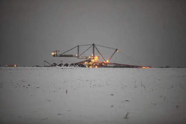 Bucket wheel excavator digging for brown coal winter night view Poland. Extractive industry