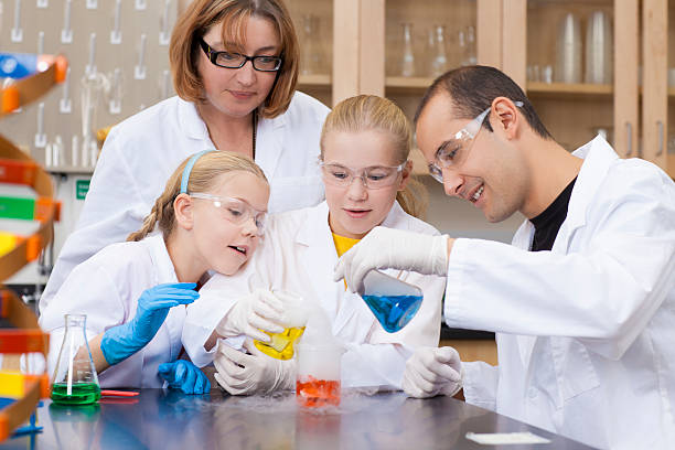 zwei junge wissenschaftler und deren mentoren im science lab - healthcare and medicine smiling group of people lab coat stock-fotos und bilder