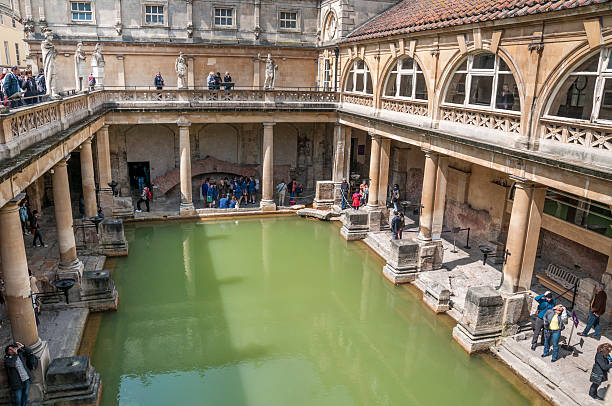 Roman Baths Bath, United Kingdom - May 17, 2013: A view of tourists walking around the main pool at the Roman Baths in Bath, England. roman baths stock pictures, royalty-free photos & images