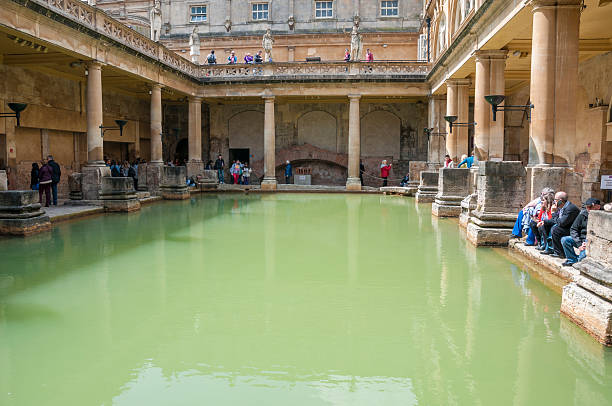 Roman Baths Bath, United Kingdom - May 17, 2013: A view of tourists walking around the main pool at the Roman Baths in Bath, England. roman baths stock pictures, royalty-free photos & images