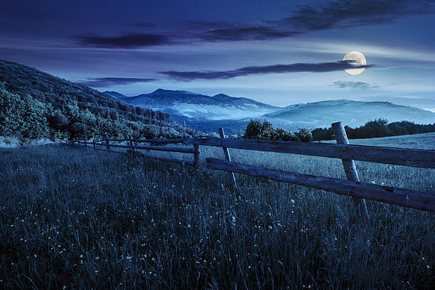 istock fence on hillside meadow in mountains at night 478138220