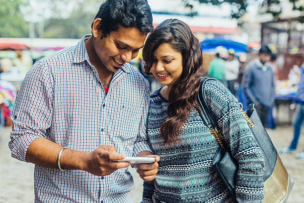 indiano feliz jovem casal olhando no celular - new delhi india indian culture indian ethnicity - fotografias e filmes do acervo