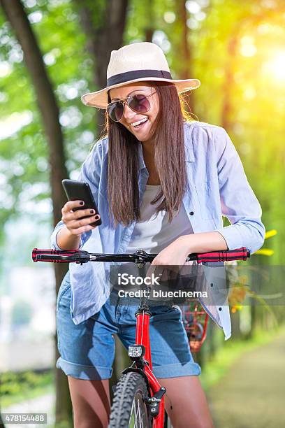 Beautiful Young Woman On Bicycle Typing Text Message Stock Photo - Download Image Now