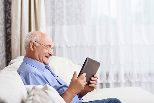 istock Senior man  sitting and holding tablet 478154516
