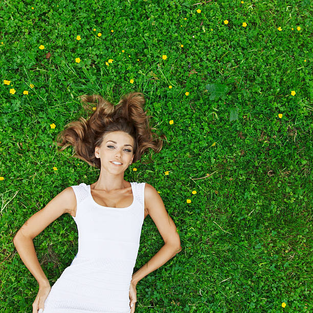 istock young woman in white dress lying on grass 478155154