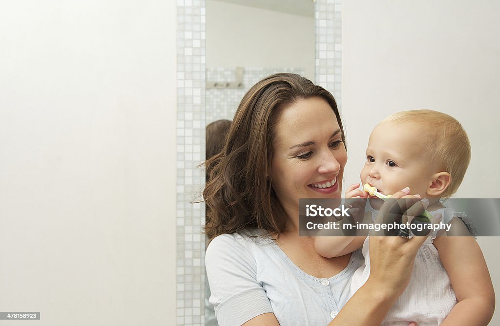 Mother teaching baby how to brush teeth with toothbrush Horizontal portrait of a smiling mother teaching cute baby how to brush teeth with toothbrush Baby - Human Age Stock Photo