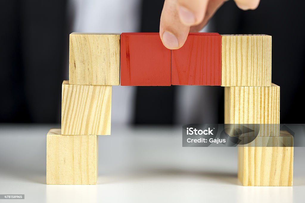 Making a bridge with wooden toy cubes Building a business concept. Closeup of businessman making a bridge with wooden toy cubes. Achievement Stock Photo