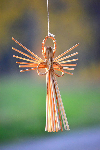 Straw angel hanging on dark blurred background filter, close-up