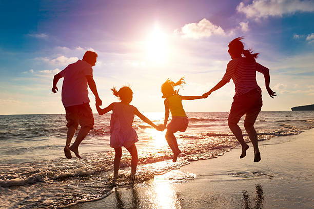 glückliches familienspringen am strand - tropical climate water leisure activity holidays stock-fotos und bilder