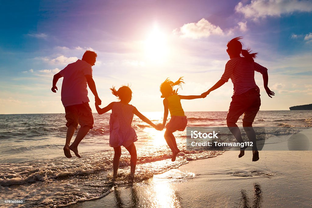 happy family jumping together on the beach Family Stock Photo