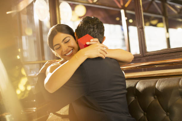 Woman with jewelry box hugging man in restaurant  ring tilt stock pictures, royalty-free photos & images