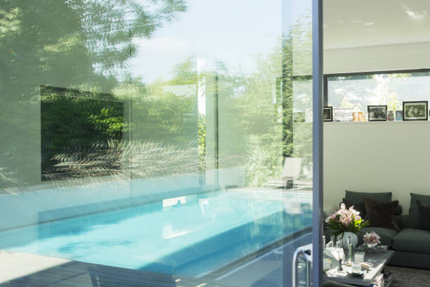 istock Swimming pool reflected in glass windows of modern house 478168155