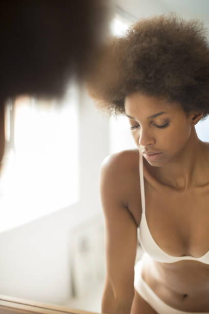 istock Woman in bra standing at bathroom mirror 478168513