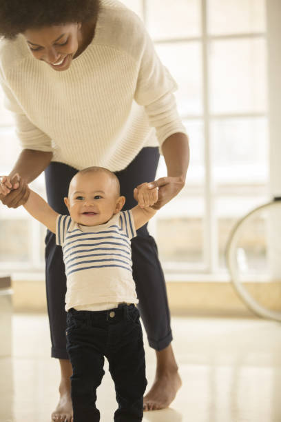 istock Mother helping baby boy walk on floor 478168595