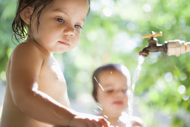 Baby girls playing in water spout outdoors  hot mexican girls stock pictures, royalty-free photos & images