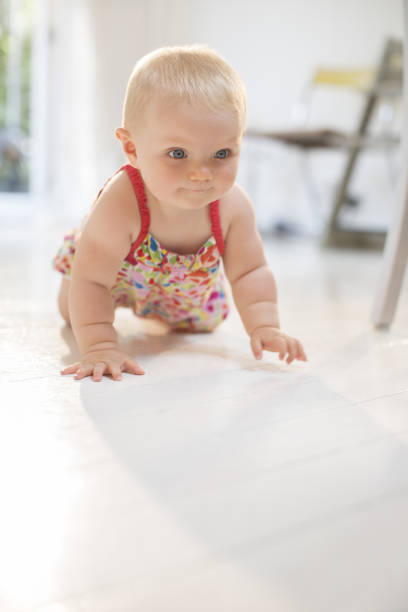 Baby girl learning to crawl. Happy healthy little child on the floor. Infant kid at home