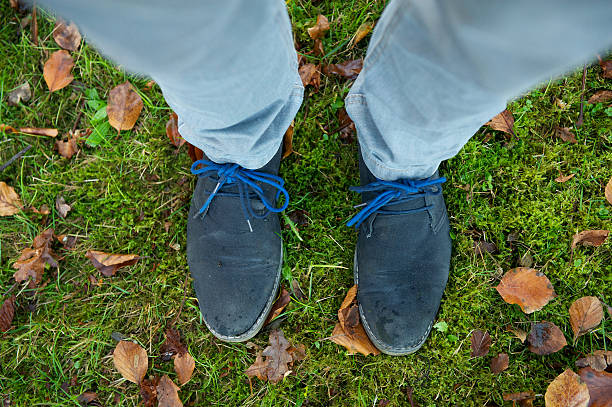 Two feet in boots standing on green grass outdoors