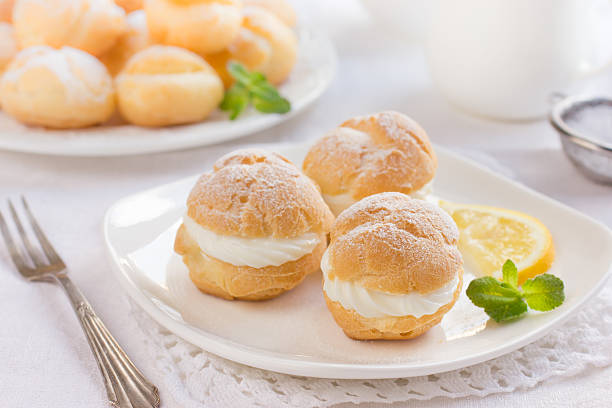 profiteroles с кремом и «powdered sugar - эклер стоковые фото и изображения